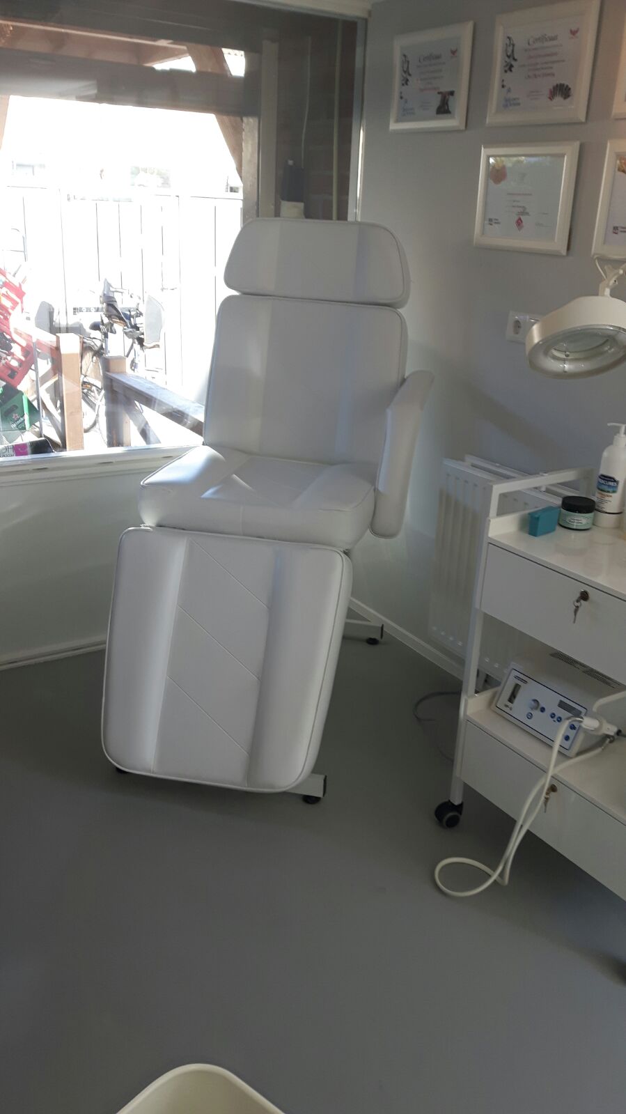 De lichte behandelstoel naast het raam in de salon
